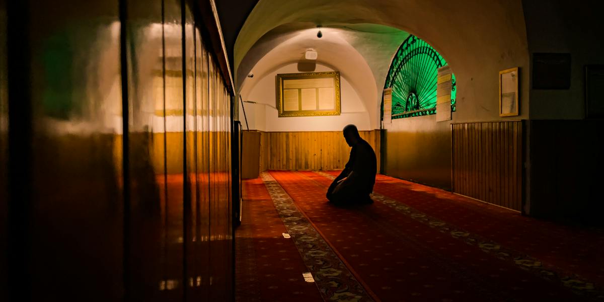 A Person Praying while Kneeling in a Mosque